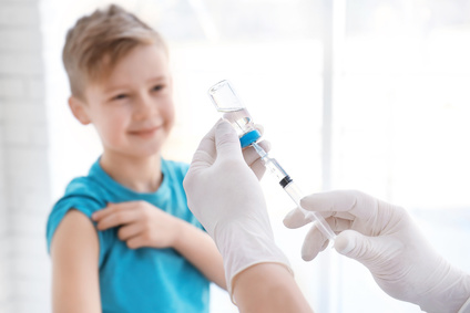 Junge schaut auf Impfspritze