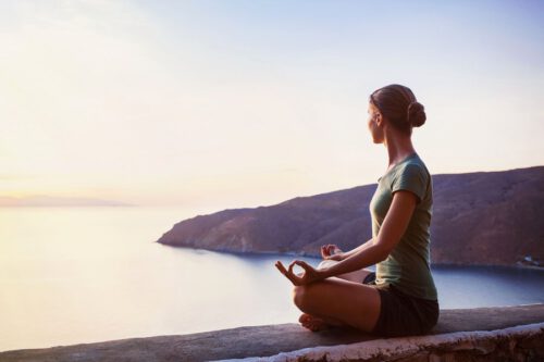 Frau macht Yoga am Wasser