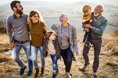 Familie mit Kindern und Großeltern lachend beim Spaziergang