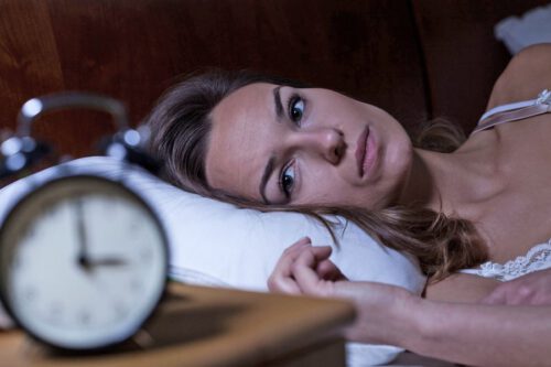 Schlaflose Frau mit Gesicht auf dem Kissen