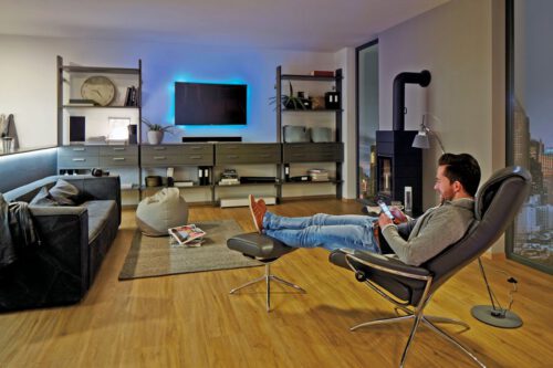 Mann sitzt im Sessel mit gemütlicher TV Beleuchtung