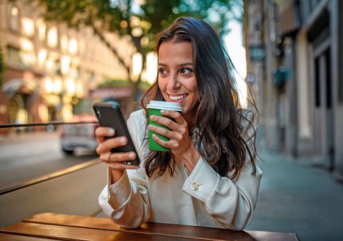 Junge Frau im Straßenkaffee mit dem Handy